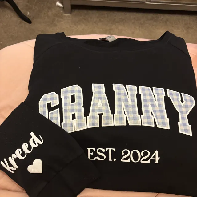 Black crewneck with GRANNY in blue gingham varsity letters, EST. 2024, and the name Kreed with a heart on the sleeve