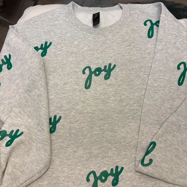 Heather grey long-sleeve covered in a green cursive joy all-over print